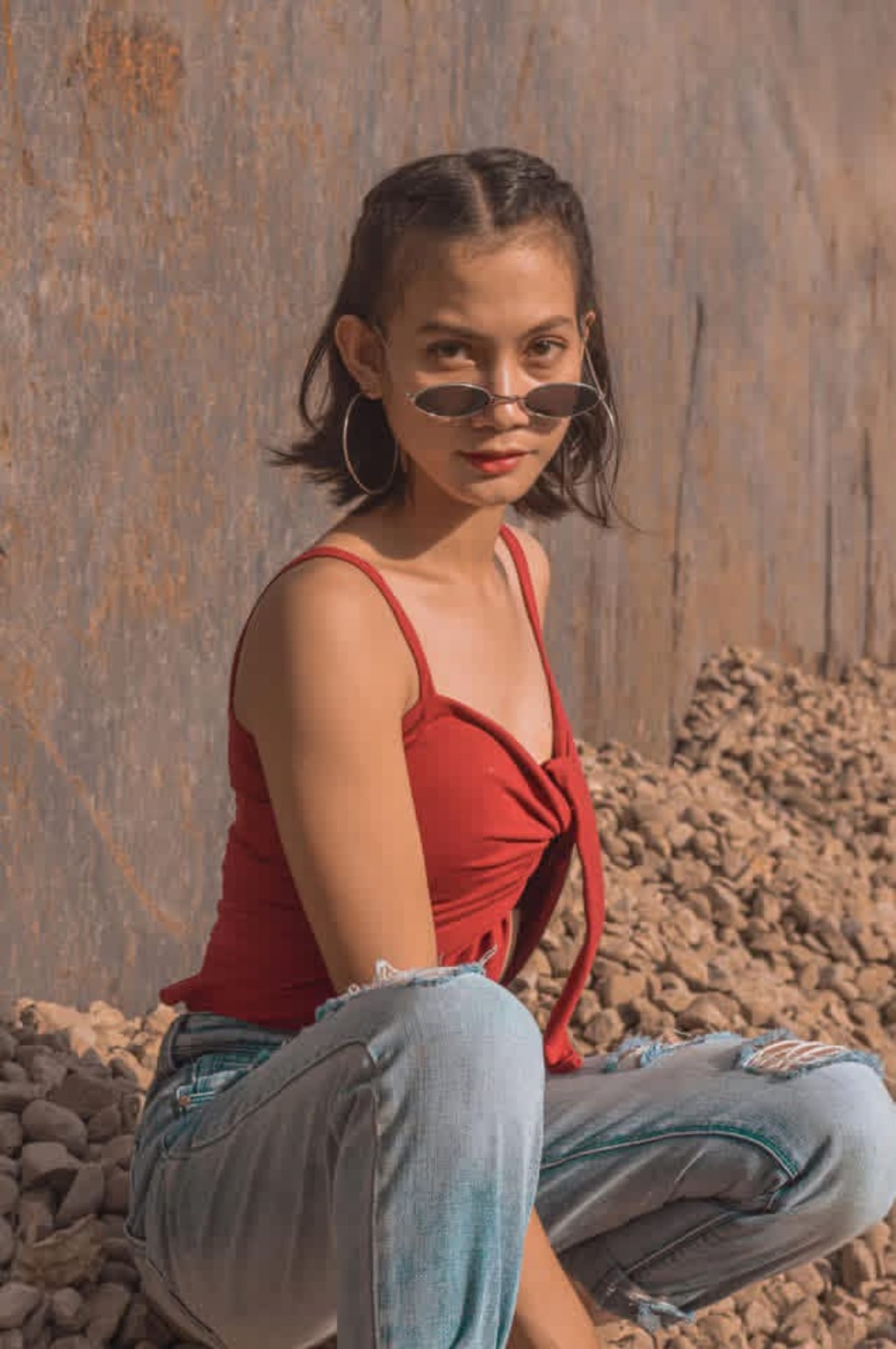 Woman in a red top seated beside a textured wall
